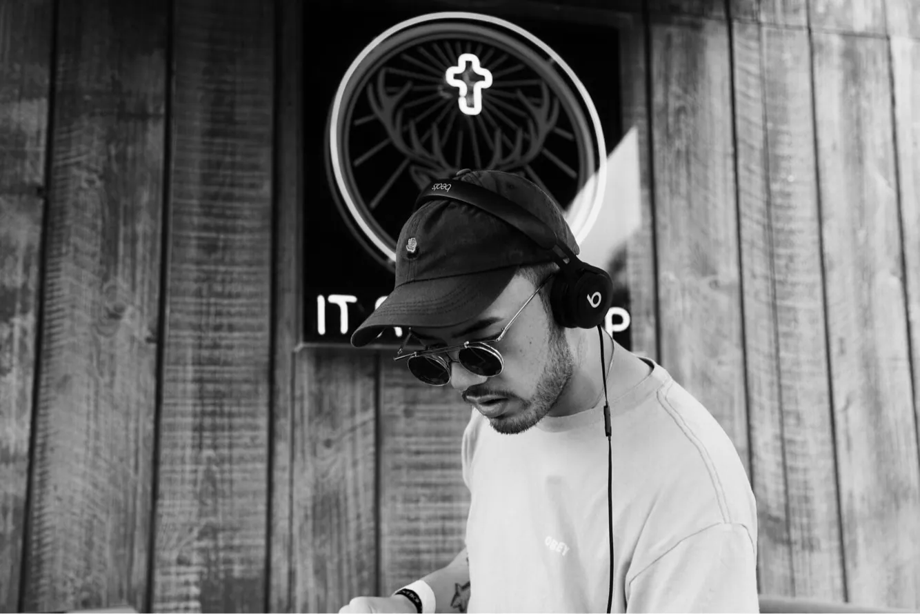 BDJ on the decks in black and white, headphones on, eyes on the mix