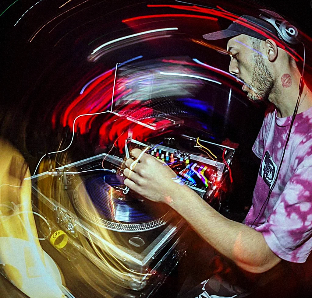 BDJ mid-set at the decks, the room smeared into streaks of red and gold light around him